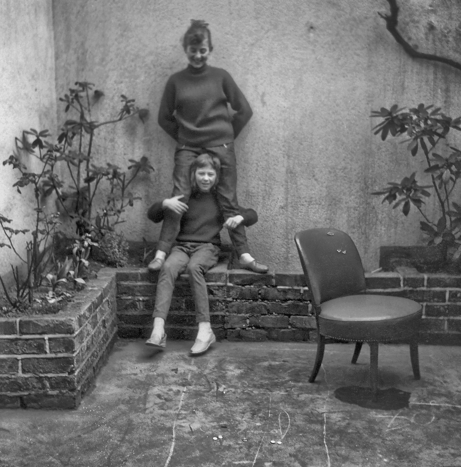 Zwei auf Pflanzeneckmauer mit Stuhl