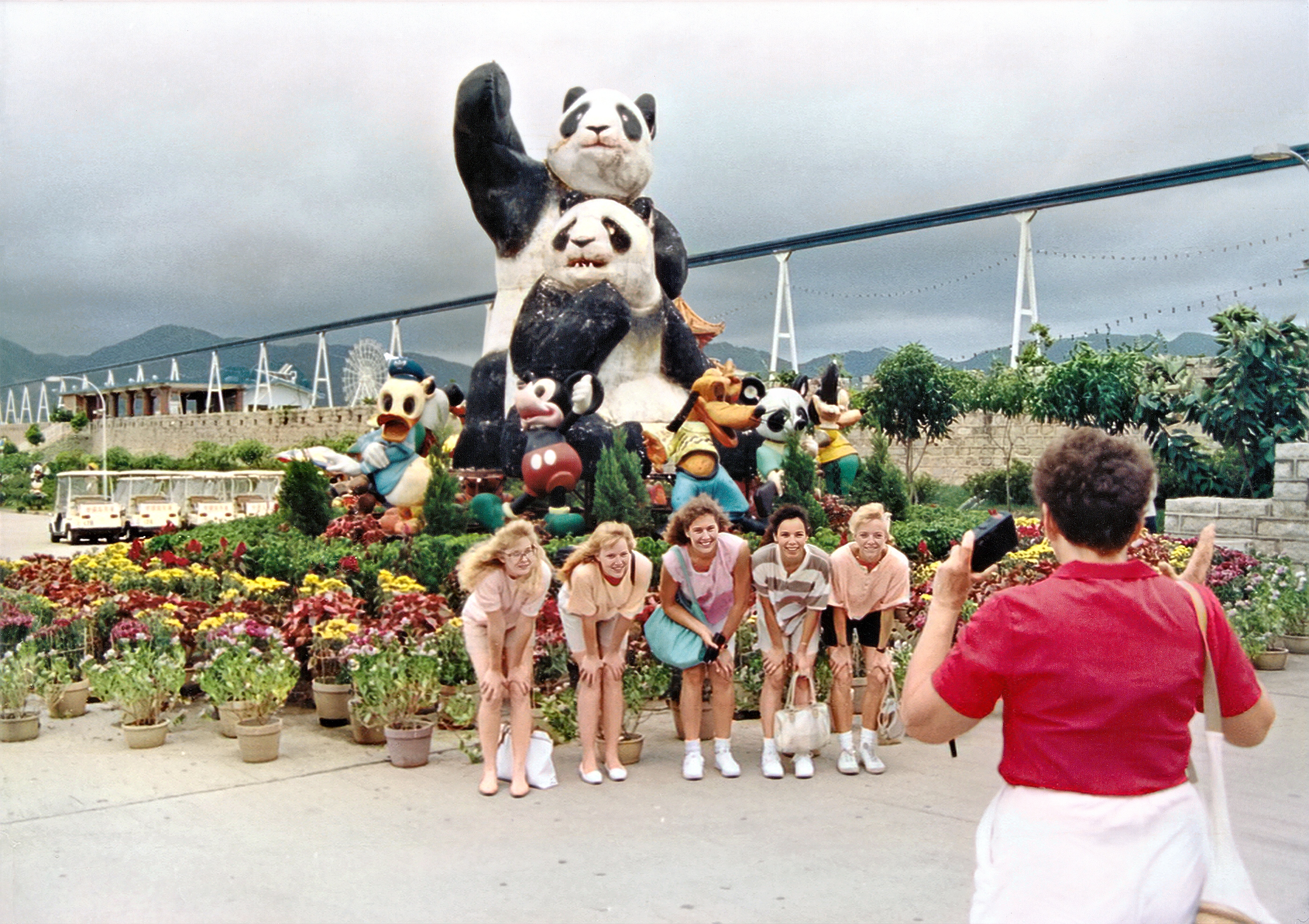 Fuenf vor Pandabaeren und Disneyfiguren am Blumenrondell