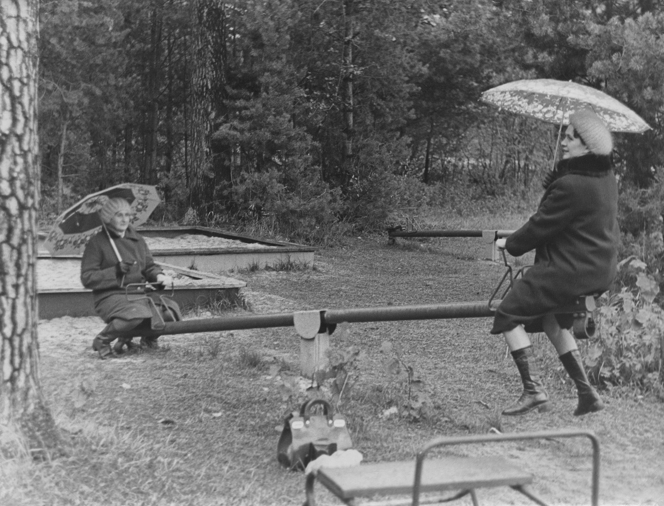 Zwei auf Wippe mit Schirmen - A