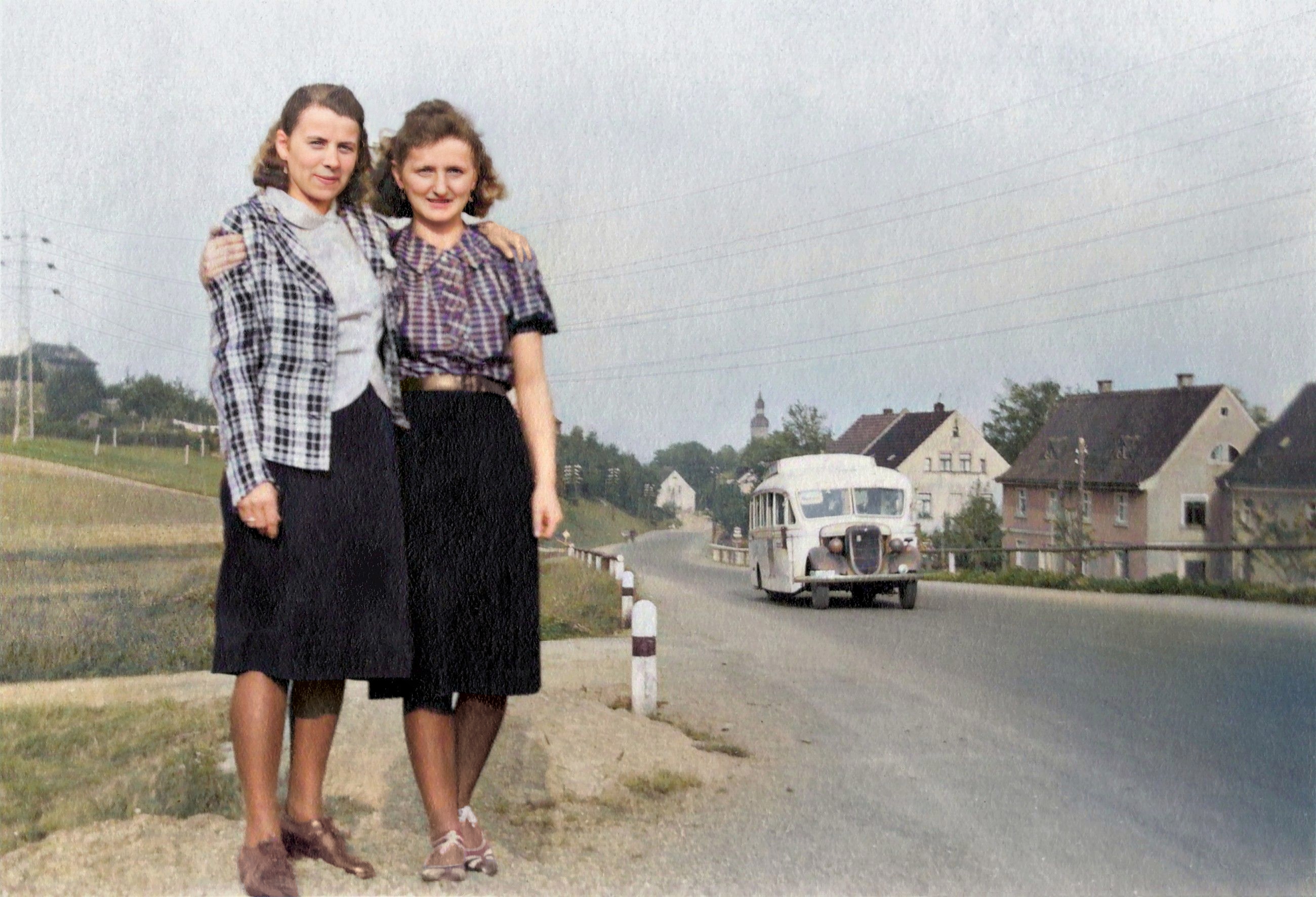Zwei vor Ueberlandleitung an Dorfstrasse mit Bus